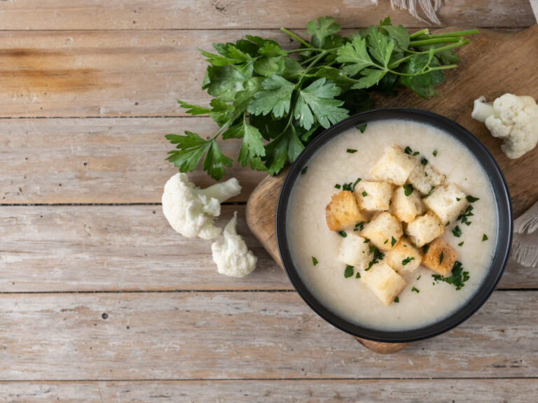 Cauliflower soup in a bowl on wooden table
